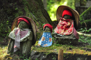 Jizo statues of different shapes and sizes, dressed in red to designate them as helpers to children who have passed away. Grieving parents often dress them as they mourn. 